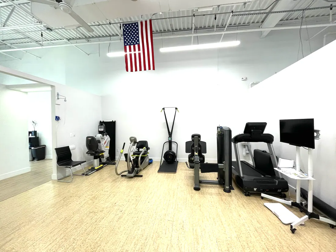 The gym at Excel Therapy, with cardio and strength machines along a bright white wall