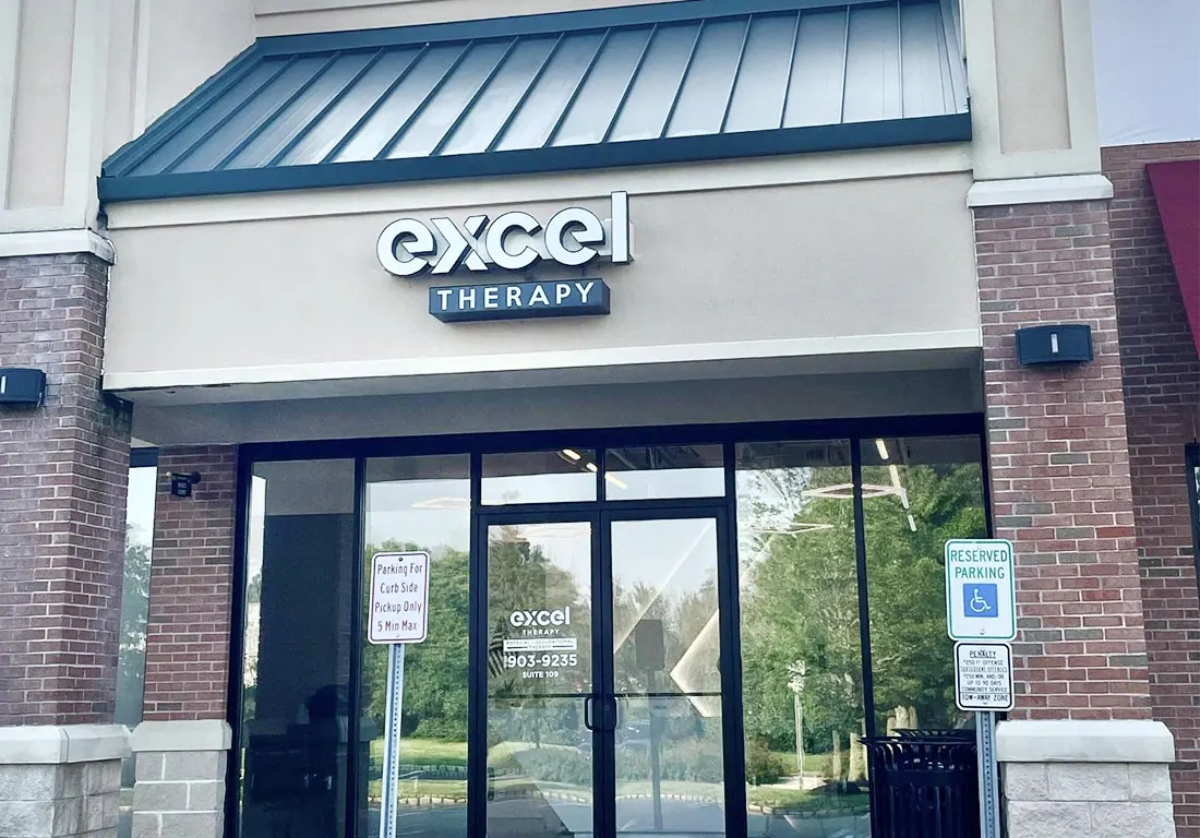 The Excel Therapy storefront: glass doors under a green awning with the Excel Therapy sign